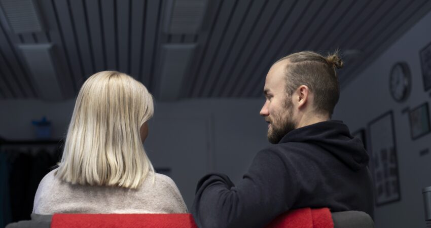 Kaksi ihmistä istuu tuolilla selin kameraan