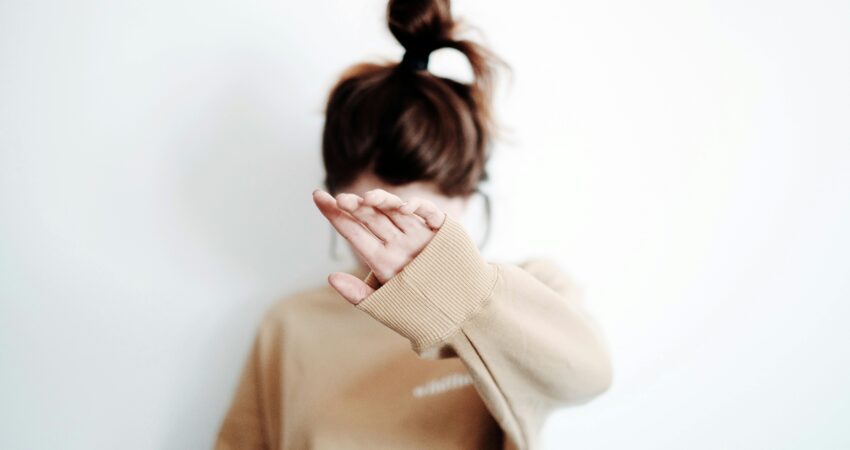 Nainen, joka peittää kasvona kädellä.