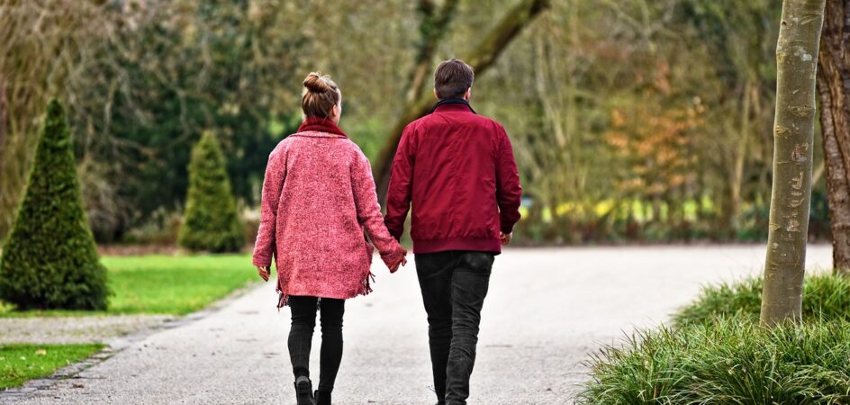 Nainen ja mies kävelee käsi kädessä.