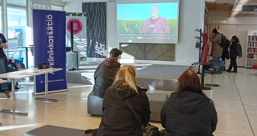 Ihmisiä katsomassa Pekan kokemusasiantuntijavideota Päihde- ja mielenterveystyön kansalaistapahtumassa Jyväskylän kaupunginkirjastossa.