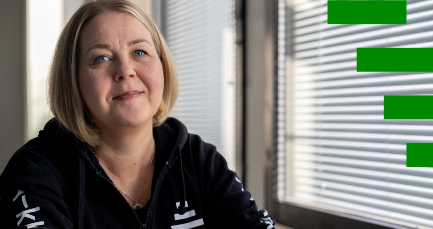 Kuvassa vaaleahiuksinen henkilö katsoo kameraan. Hän istuu ikkunan ääressä ja yllään musta huppari, jossa lukee A-klinikkasäätiö