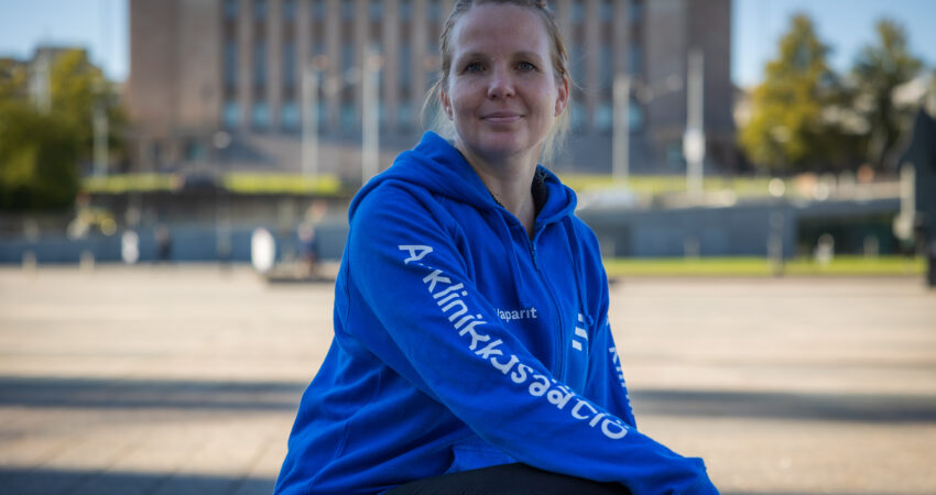 Kuvassa henkilö Eduskuntatalon edessä. Hänellä on päällään sininen huppari, jossa lukee A-klinikkasäätiö