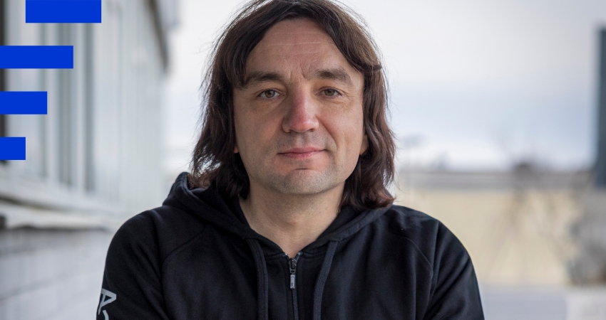 Kuvassa tummahiuksinen henkilö katsoo ulkotiloissa suoraan kameraan