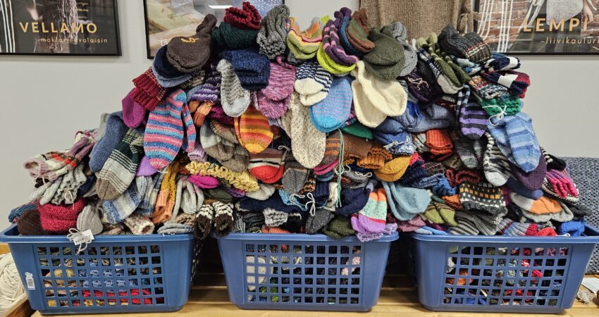 Kolme sinistä muovikoria täynnä villasukkia, joita on kerätty Lahjoita lämpöä -kampanjassa