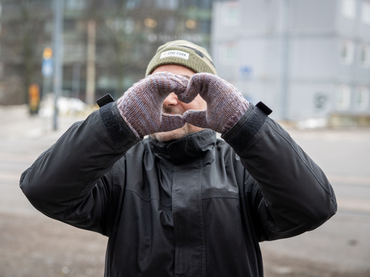 Kuvassa henkilö tekee käsillään sydämen. Hän on ulkona pakkasessa lapaset kädessä