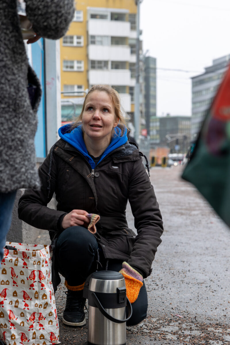 Kuvassa A-klinikkasäätiön asiantuntija Pihla Valkeala kadulla jalkautumassa. Hän on juuri antamassa kahvia apua tarvitsevalle ihmiselle