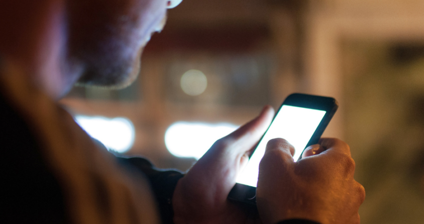 mies näpyttelee puhelinta