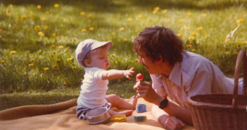 Lapsi ja isä leikkimässä viltillä pihalla