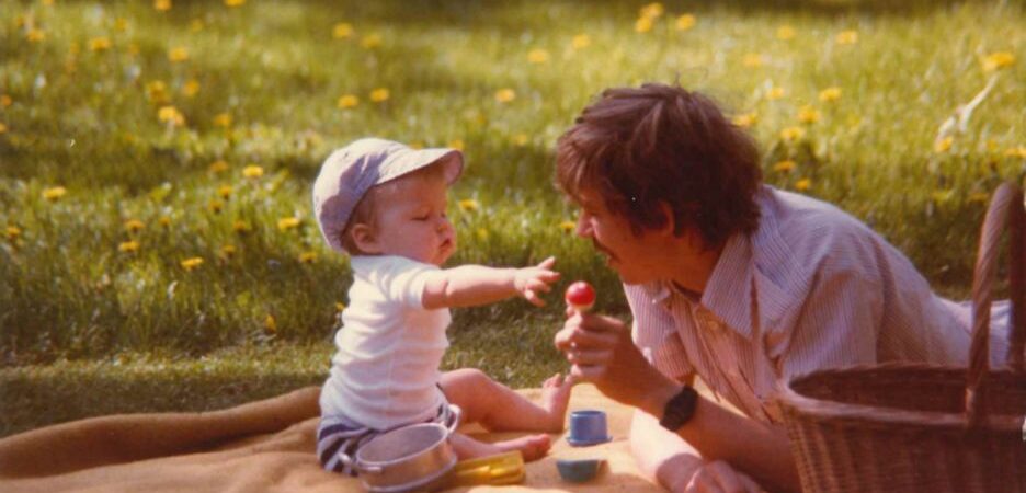 Lapsi ja isä leikkimässä viltillä pihalla