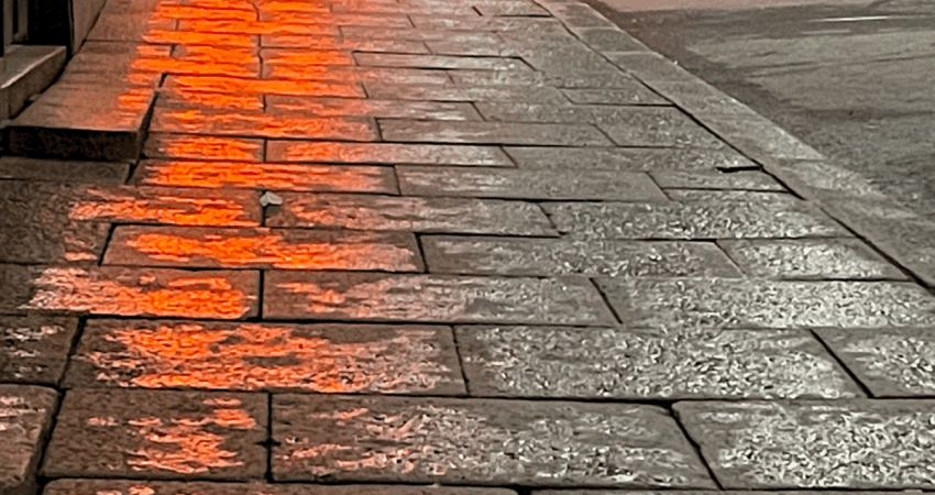 baarin valot heijastuvat märkään katukivetykseen