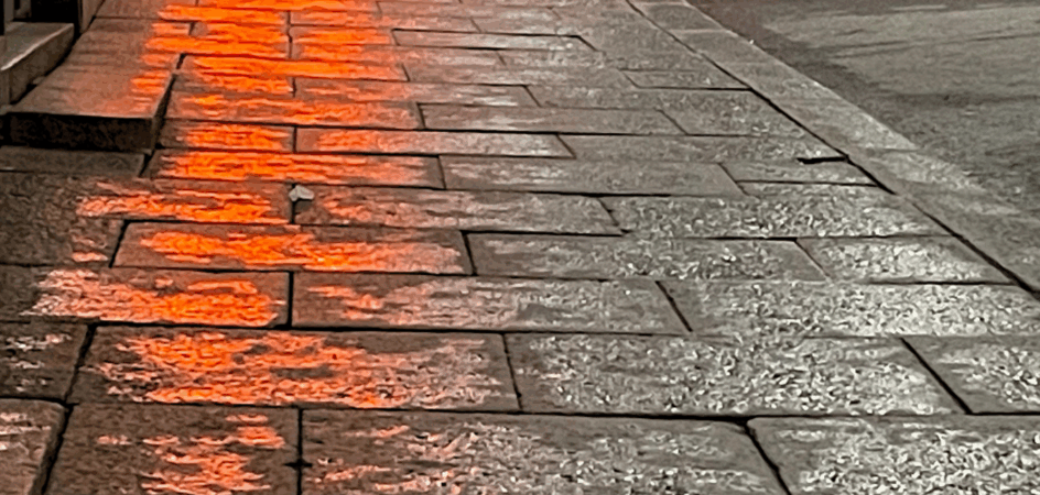 baarin valot heijastuvat märkään katukivetykseen