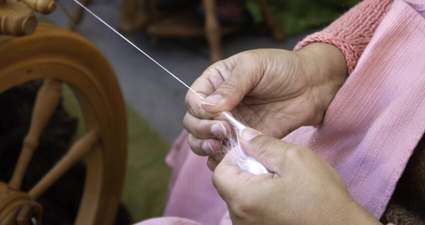 Kädet kehräämässä lankaa rukilla