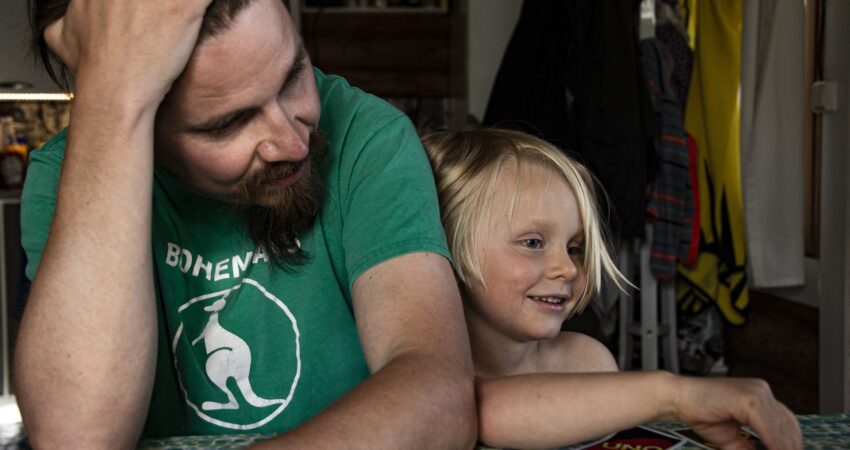 Isä ja lapsi pöydän ääressä pelaamassa Unoa