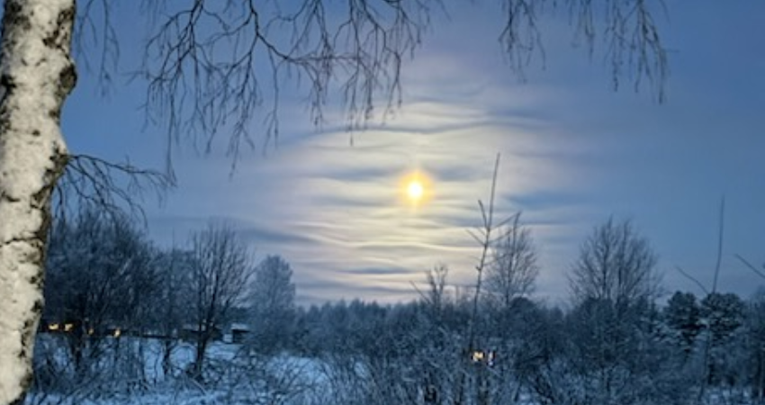 aurinko kajastaa pilvien lomasta talvisessa maisemassa